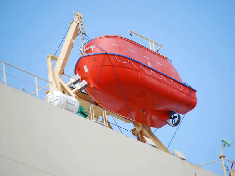 An enclosed lifeboat stowed in its davit on a ship's side